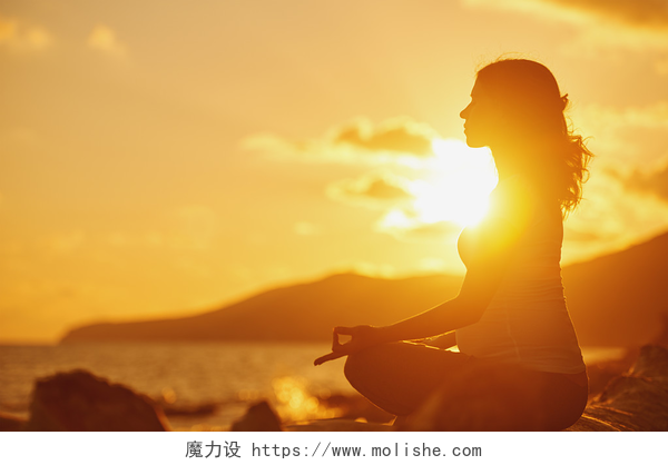 在夕阳下孕妇练着瑜伽孕妇练瑜伽在荷花在阳光沙滩上的立场